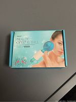 Photo showing Beauty Crystal Ball facial massager in unopened retail box, blue globe head with white handle and marketing image on box.