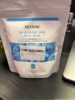 Pack of MooYam Hyaluronic Acid Jelly Mask sitting next to laptop, displaying front of white and blue resealable bag with text and label.