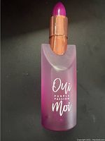 Close up of the perfume bottle showing 'Oui Moi Purple Passion' text and gradient purple frosted glass with lipstick-shaped cap.