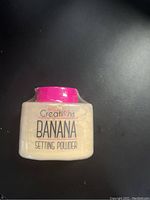 Photo of Creations Banana Setting Powder container with pink cap on black background, unopened