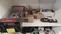 Shelf with multiple door handles and lock hardware, some in boxes including Kwikset.
