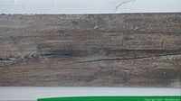 Single vinyl plank showing wood-grain texture and grey-brown tone.