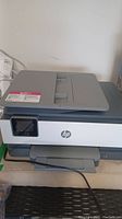 Front angle view of HP OfficeJet Pro 8025 printer showing touchscreen and paper trays.