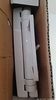 Close-up side view of two white toilet seats stacked inside the box.