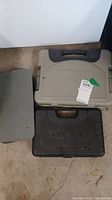 Three plastic cases on the floor: beige, gray, and black Black & Decker case