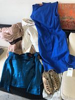 Lot items displayed including blue dress, teal jacket, patterned coat, tan Munro shoes, and other garments on a couch
