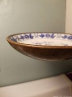 Side view of a dish showing patina metal backing around the porcelain rim.