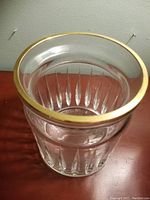 Close-up photo of cut crystal jar showing fluted vertical pattern and gold-tone metal rim from top view.