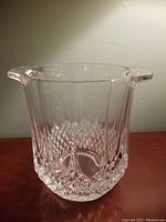 Front view of clear cut glass ice bucket showing geometric pattern and handle on one side