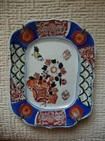 Full view of rectangular scalloped edge plate showing central floral motif with crawling child and detailed blue and red borders.