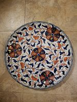 Top view image showing full surface design of the shallow scalloped edge plate with floral pattern in blue, orange and white.
