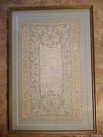 Full view of vintage handmade lace in frame showing the entire piece and gold frame with teal double matting.