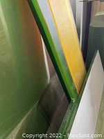 Close-up photo of a vertical stack of assorted acrylic sheets in distinct colors including green, yellow, and translucent/clear sheets.