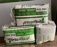 Photo showing three bundles of Green Fiber blow-in insulation, two full bundles and one half bundle, all in plastic packaging with R12-R60 rating visible.