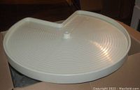 Photo showing one beige plastic lazy susan tray with raised edges and central hole for rotation mechanism, designed for kitchen cabinet corner units.