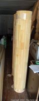 Three tall fluted wood columns leaning vertically in a storage area, showing smooth vertical grooves and segmented wood construction with light natural finish.