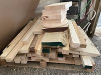 Photo showing a stack of assorted wood offcuts including rectangular and rounded pieces piled on a pallet in a workshop area.