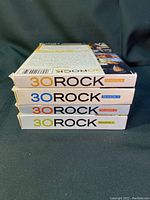 Stack of 30 Rock DVD cases showing the spines with season numbers 1 through 4.