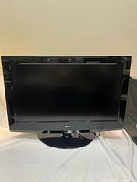Front view of 32-inch LG television showing screen and black glossy frame on spinning base.