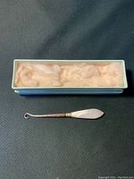 Photo of crochet needle with mother of pearl handle and original box with padding