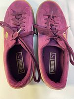 Top-down view of purple suede Puma sneakers showing laces, interior branding, and overall shape.