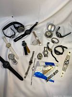 Photo showing large collection of wristwatches in various styles, including leather, metal, and rubber bands, some with plastic pouches of watch bands.