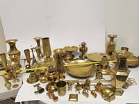 Wide view of the brass items laid out with measuring tape showing width over 3 feet.
