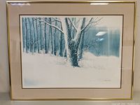 Framed print showing the winter snowy tree scene with blue and white tones and gold-tone frame with light scuffs.