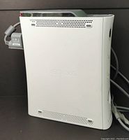 Side profile of white Xbox 360 console showing scuff and ventilation holes