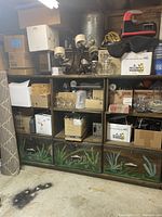 Photo of a large wooden shelf with multiple compartments and three bottom drawers, showing storage use and signs of wear.