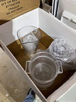 Photo of a box containing clear plastic containers including ice buckets and measuring cups.