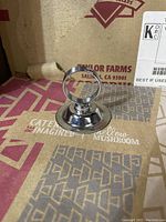 Close up photo of a single shiny chrome metal restaurant table topper showing circular base and upright ring for label insertion.