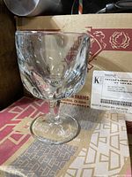 Close-up of a single clear glass 10oz gauntlet with textured pattern on bowl, sitting on cardboard box