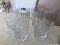 Photo showing six clear Atlantis crystal beverage glasses arranged together on a light cloth surface with vertical line patterns.