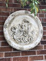 Full front view of round medallion hung on brick wall