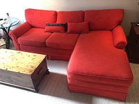 Front view of red upholstered sofa with chaise on right side