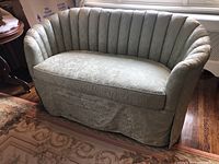 Front view of shell back settee showing floral damask upholstery and channel tufted backrest