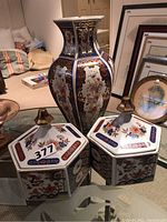 Photo showing the 13-inch Italian ceramic vase flanked by two hexagonal ceramic trinket boxes with lids on a glass table, reflecting detailed floral and geometric patterns in blue, red, gold and white.