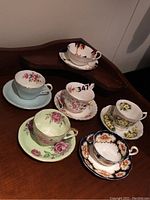 Six vintage English porcelain tea cup and saucer pairs showing a variety of floral and decorative patterns.