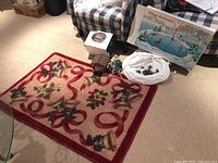 Photo showing the holiday themed carpet along with the Dickens Village house and skating pond items on the floor.