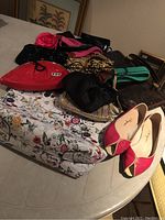 Image of assorted ladies handbags, belts, and a pair of pink and cream Ferragamo flats on a table.
