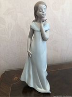 Front view of the 8-inch Lladro porcelain figurine 'A Special Occasion' showing the young woman in a pale blue flowing dress holding a pink rose near her face.