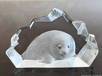 Front view of clear crystal paperweight showing etched seal inside with faceted edges.