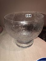 Side view of clear textured glass bowl showing bark-like surface pattern and pedestal base