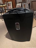 Front view of black Bonsaii paper shredder showing rectangular transparent window and power cord on top.