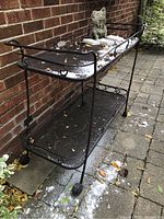 Front side view showing two-tier mesh shelves, scrollwork rails, bottle holders and caster wheels
