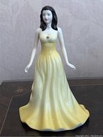Front view of the Royal Doulton figurine showing full yellow gown and gemstone detail on bodice.