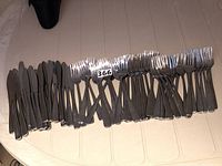 Photo showing a set of stainless steel knives, approximately 14 pieces, laid out side by side on a table.