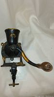 Antique cast iron coffee grinder with wooden handle and funnel hopper, viewed frontally showing 'London' mark and clamp mounting base.
