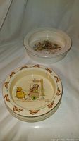Pair of antique child bowls displayed together, showing the interior designs with Bunnykins on one and Jack and Jill nursery rhyme on the other